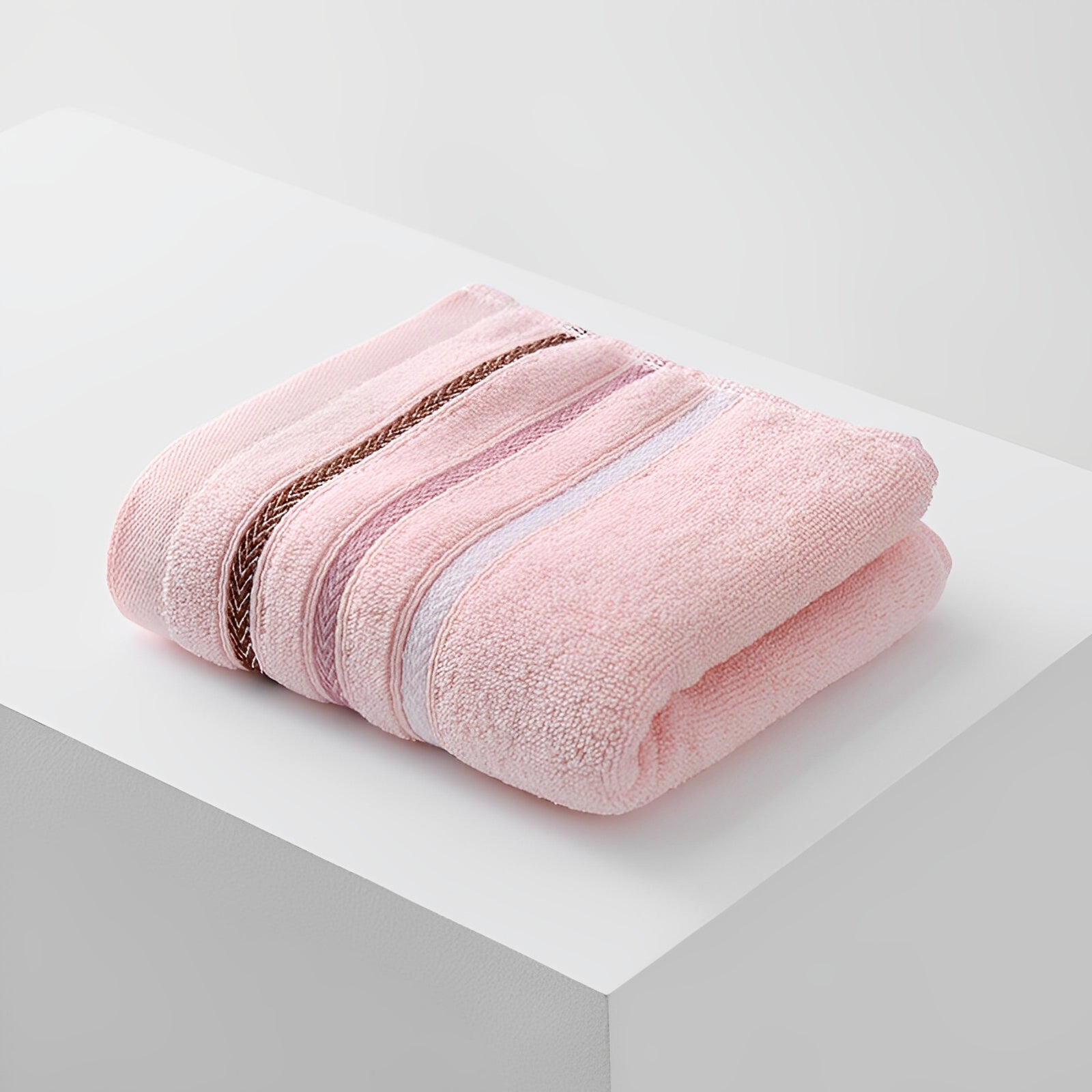 The Handduk med Ränder - Rosa från Elevkassan, tillverkad i mjukt frottématerial med dekorativa ränder, ligger prydligt vikt på en vit yta mot en ljus bakgrund.