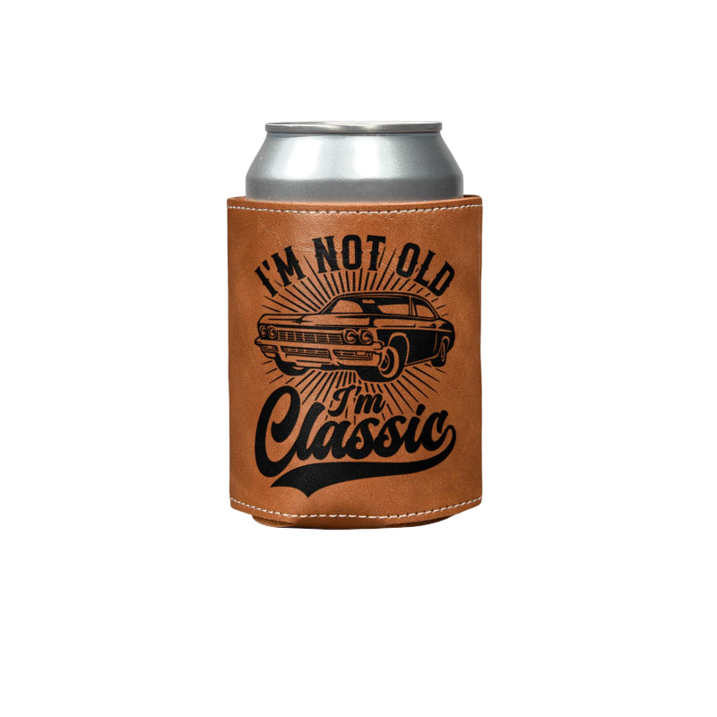 Elevkassan Roliga Dryckeskylarhållare är en brun burkhållare i läder med en silverfärgad burk, en svart illustration av en klassisk bil och den feta texten "IM NOT OLD, IM Classic" - en perfekt rolig present till alla bilentusiaster.